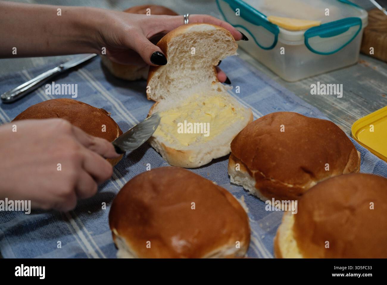 Spreading Butter on Fresh Bread Rolls in the Kitchen Stock Photo
