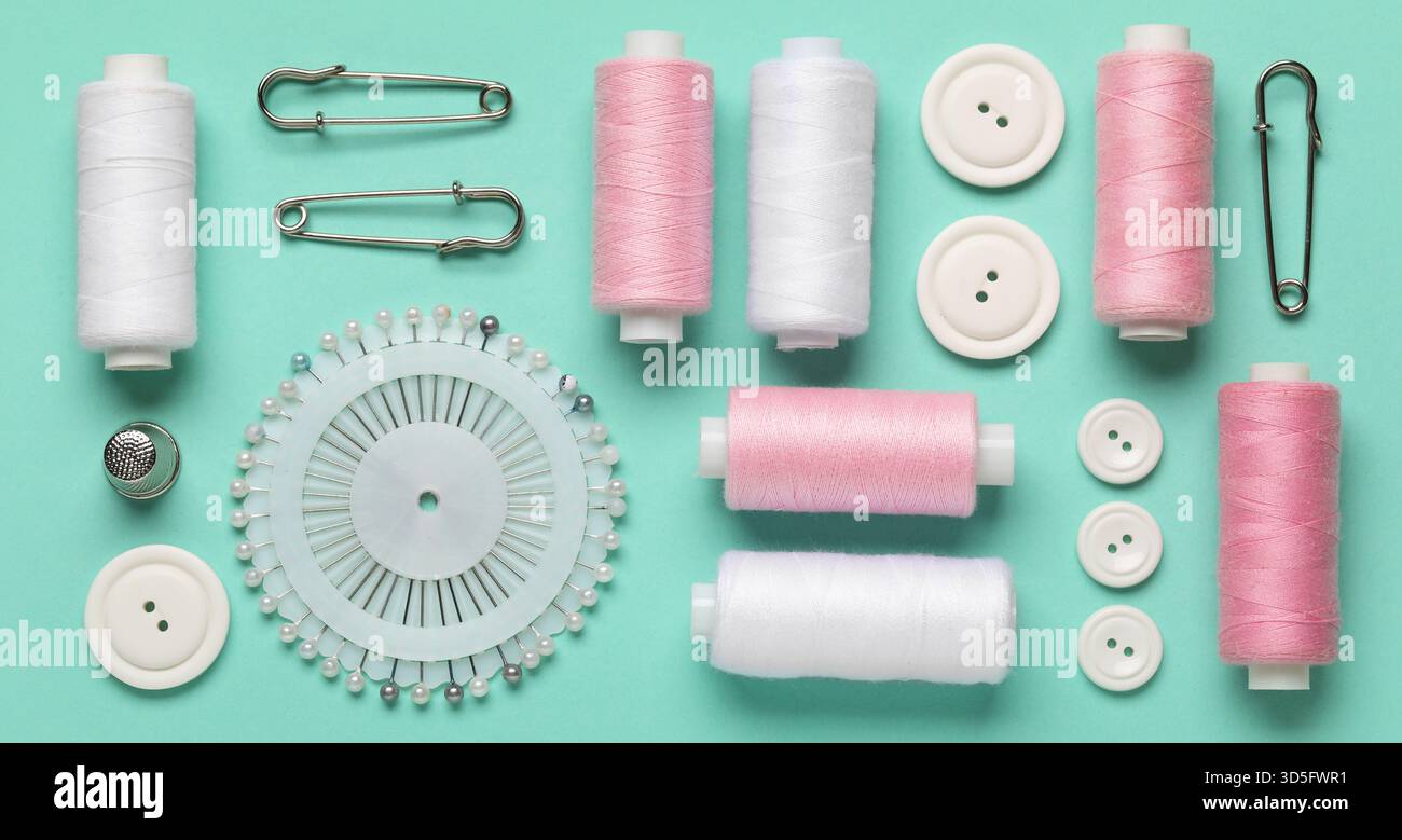 Thread spools, pins and buttons on turquoise background Stock Photo