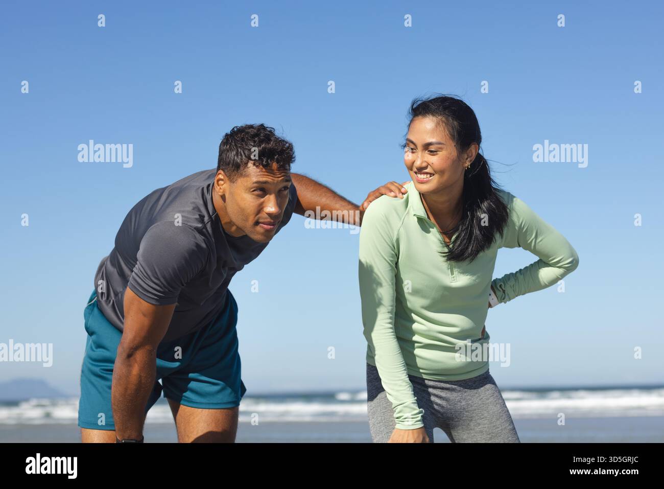 Couple enjoying outdoor exercise on beach, smiling and feeling energized Stock Photo