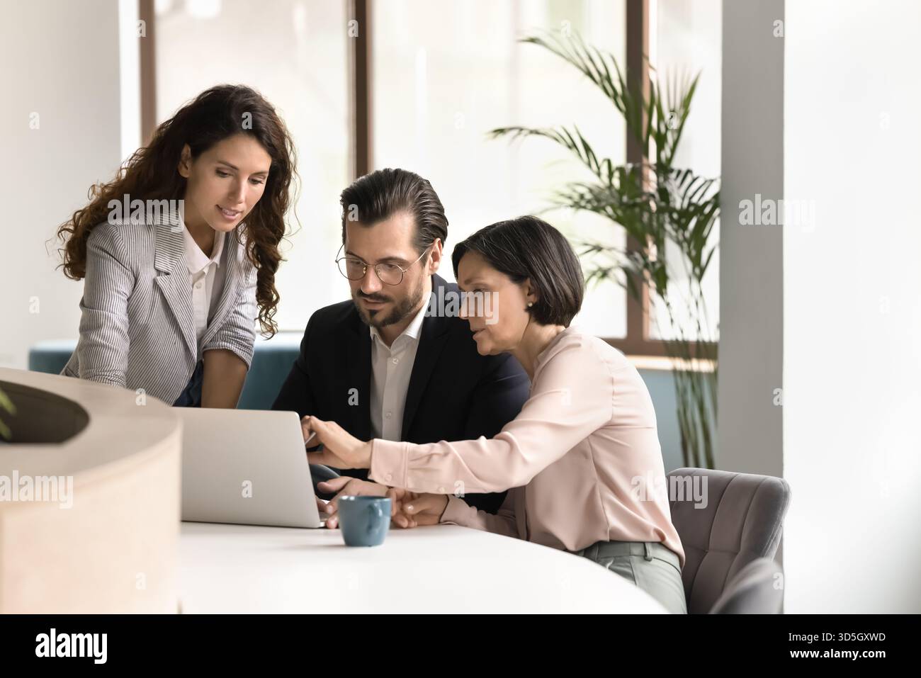 Three diverse business professionals work together on project using notebook Stock Photo
