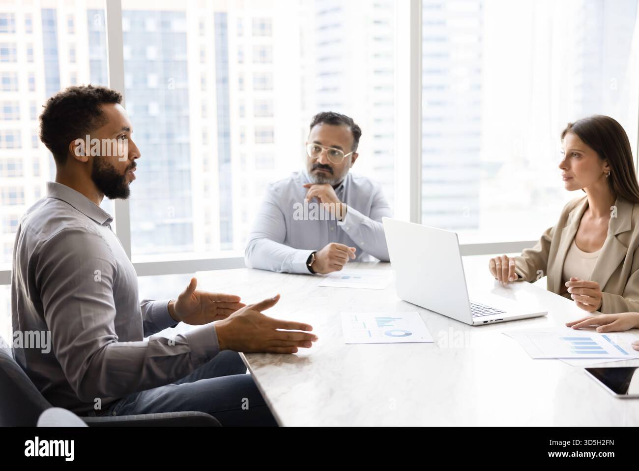 Diverse team of different aged coworkers talking at negotiation table Stock Photo