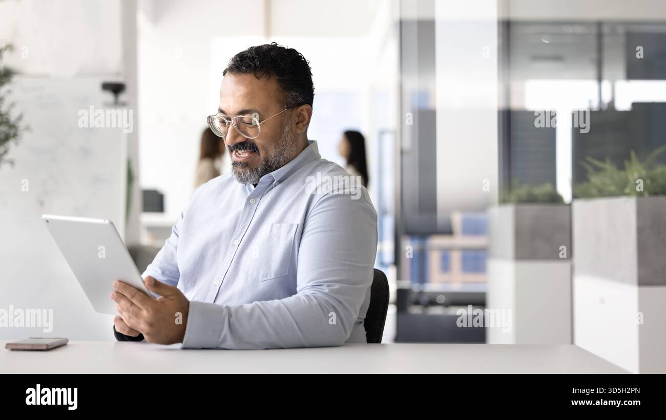 Happy mature Indian business professional man using financial application Stock Photo