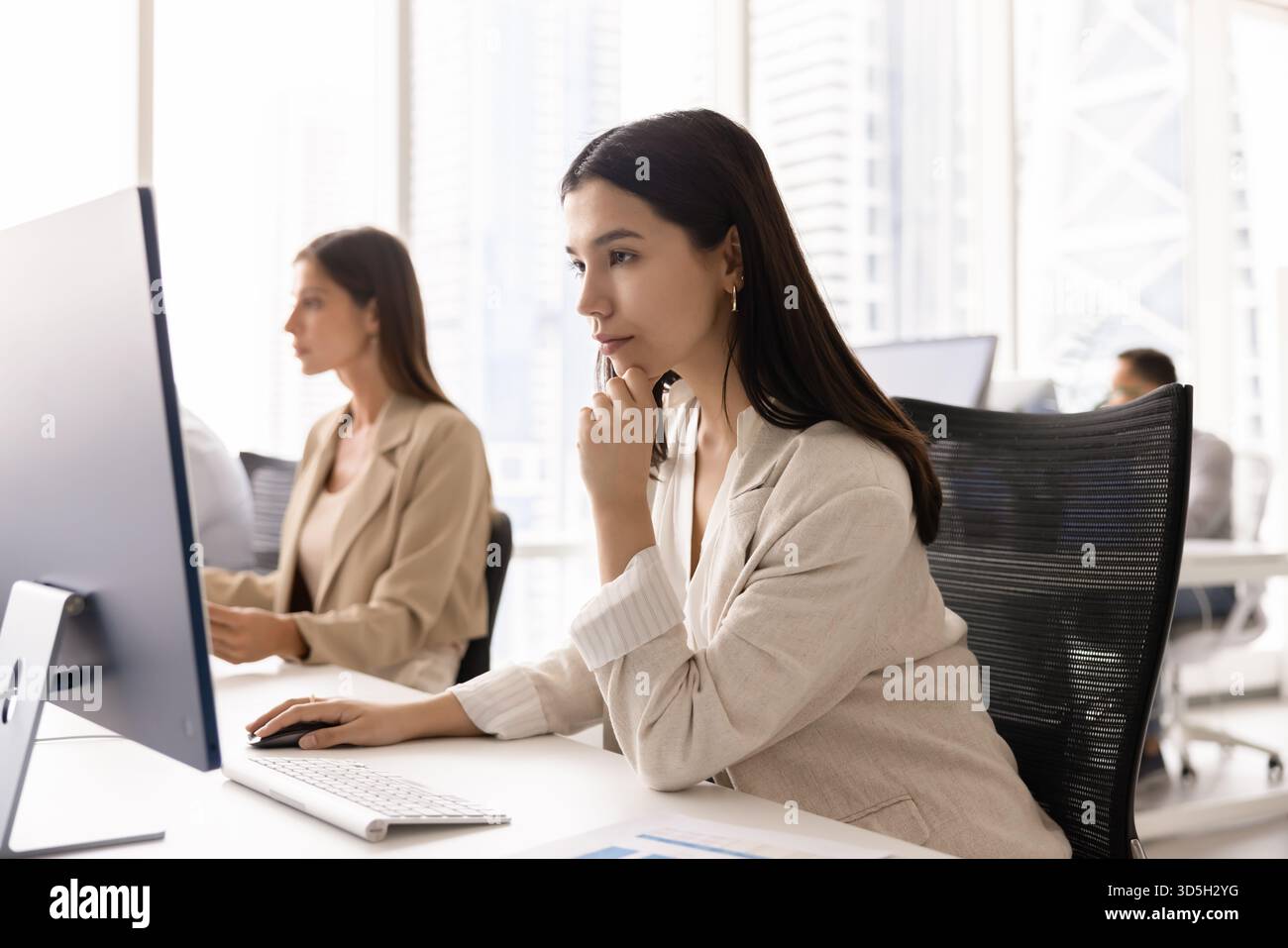 Focused pensive young business professional woman working at pc monitor Stock Photo