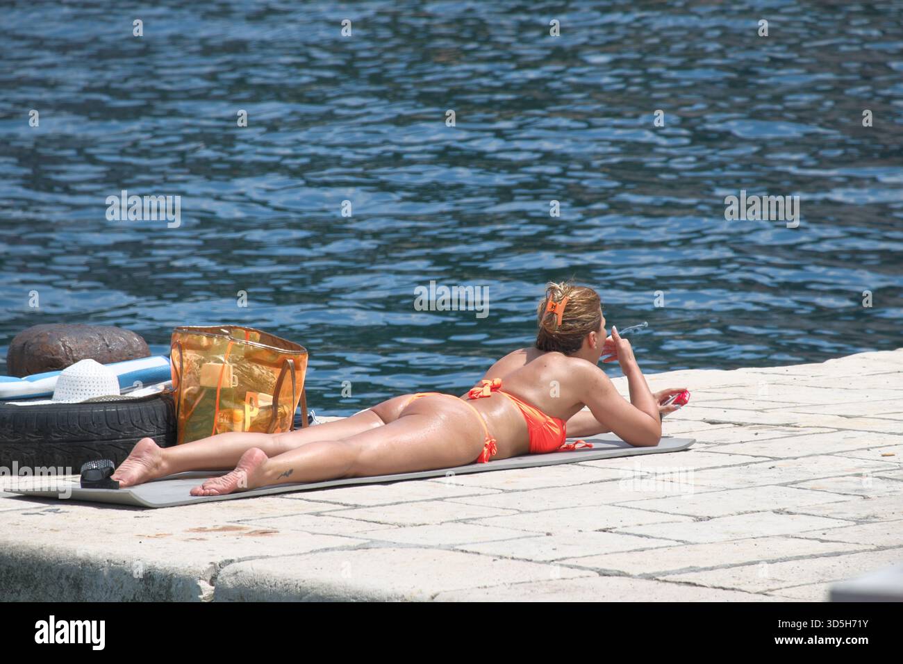 woman in bikini smoking cigarette, Kotor Bay, Montenegro Stock Photo