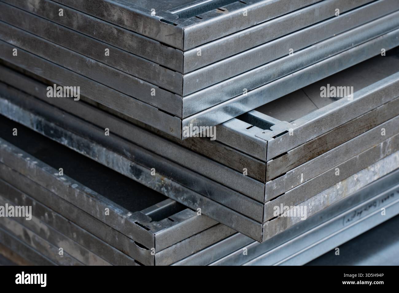 Galvanized metal formwork sheets placed in compact aligned stack showing reinforced borders, straight edges and solid panel bodies prepared for demand Stock Photo