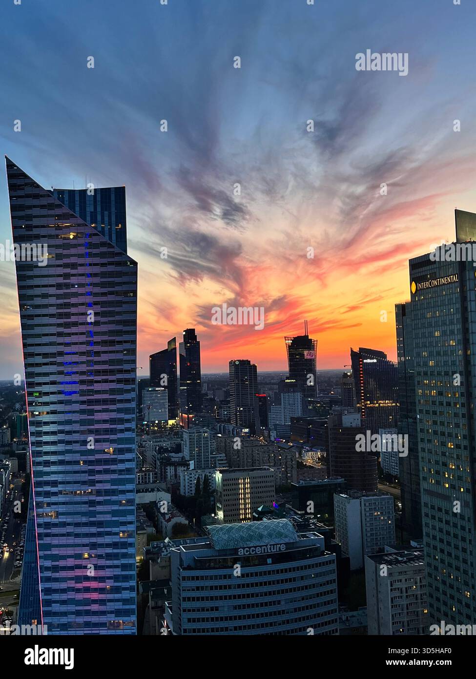 Panoramic view of Warsaw skyline under a vivid sunset sky with modern high-rise buildings. Dynamic cityscape showing the energy of Poland’s capital. - Smartphone Captured Stock Image