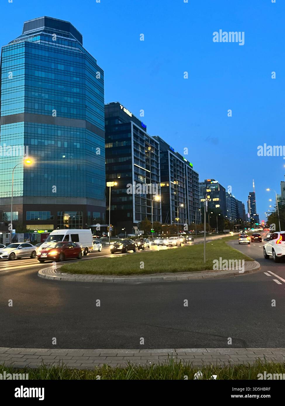 Contemporary office buildings and busy roadway in Warsaw’s modern business district during evening hours. Financial center and corporate architecture - Smartphone Captured Stock Image