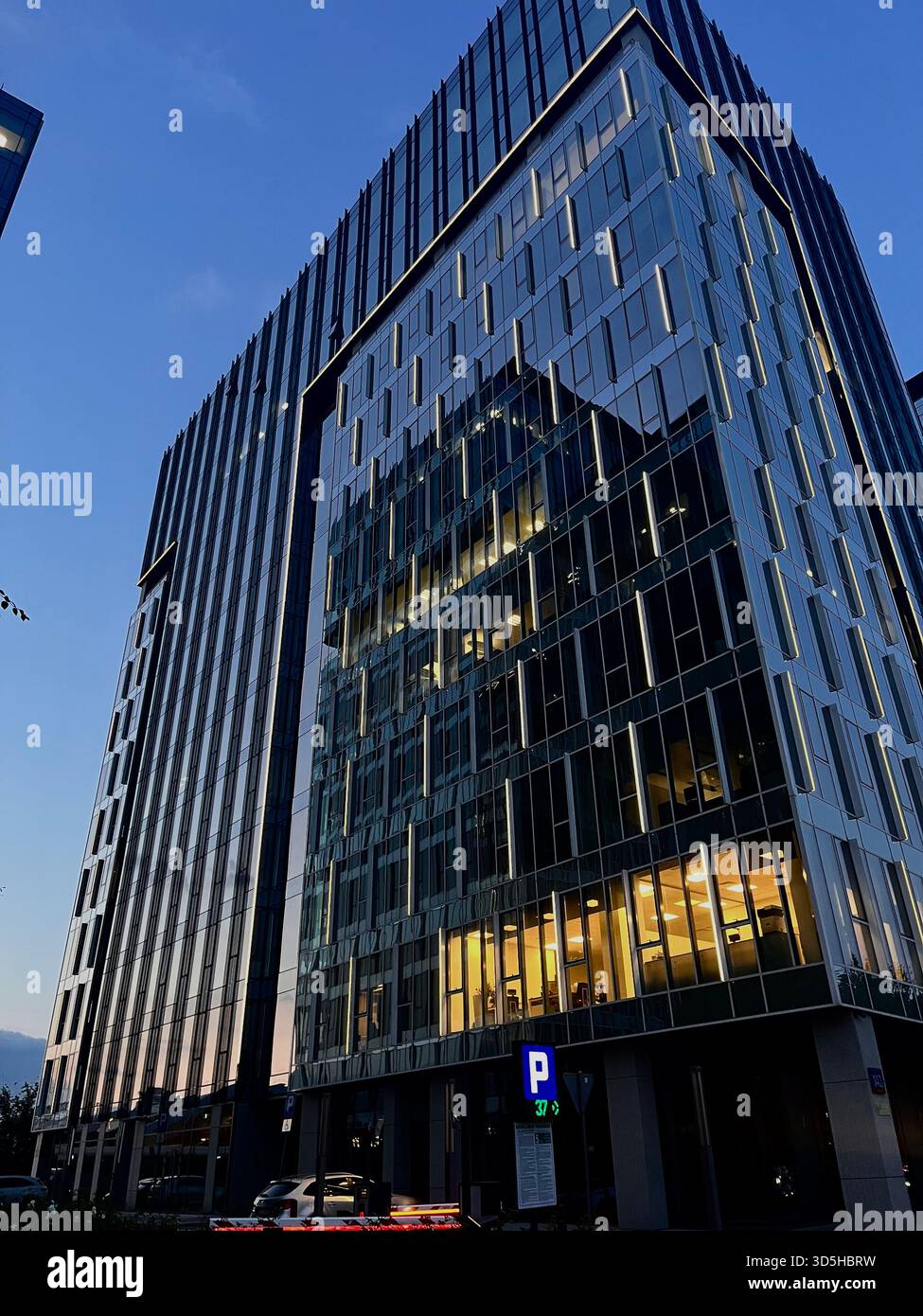 Low-angle view of a modern glass office building in Warsaw, showcasing contemporary architecture and urban growth in Poland’s capital city. - Smartphone Captured Stock Image