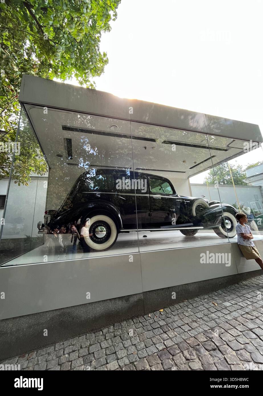 Classic vintage automobile exhibited inside a modern glass pavilion in Warsaw. Automotive history and contemporary museum-style architecture in Poland - Smartphone Captured Stock Image