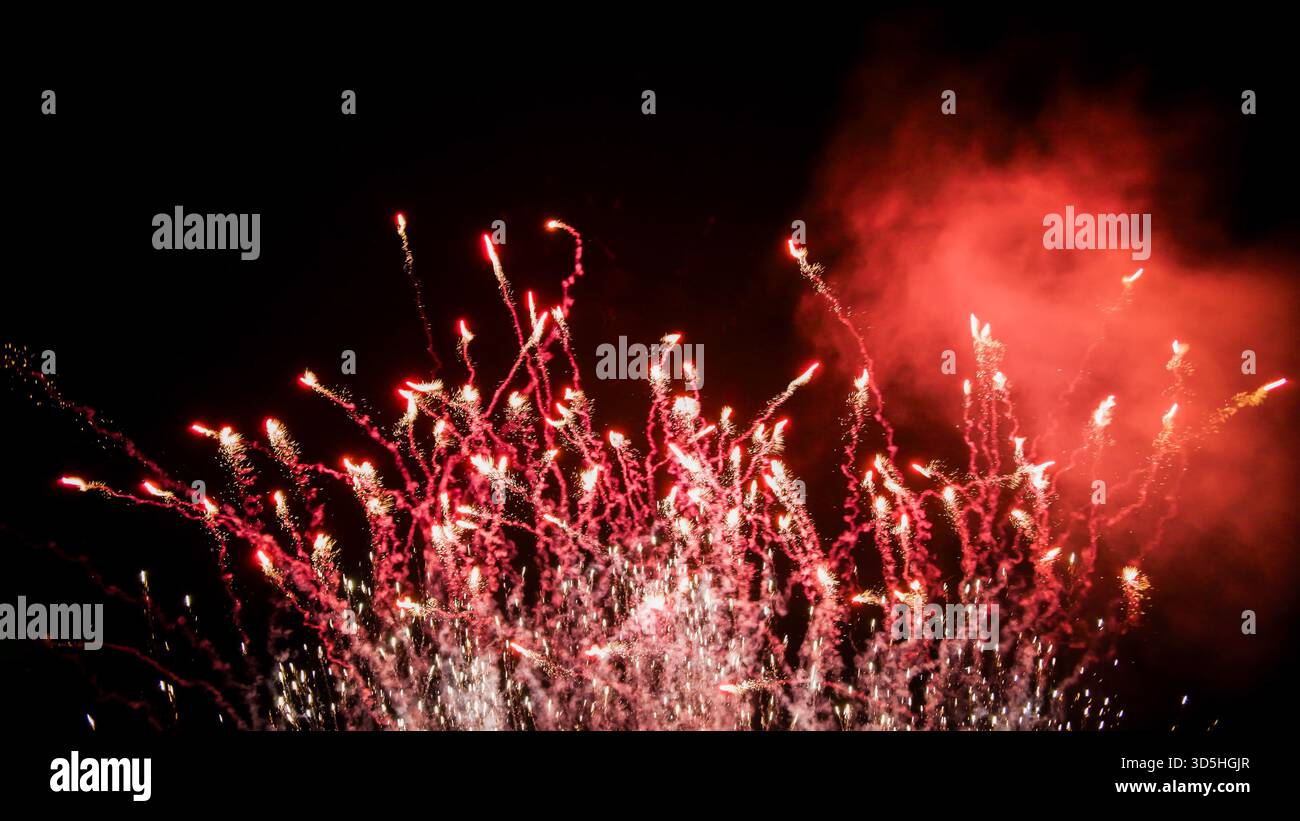 Vibrant Red and Silver Fireworks Exploding Against Night Sky Stock Photo