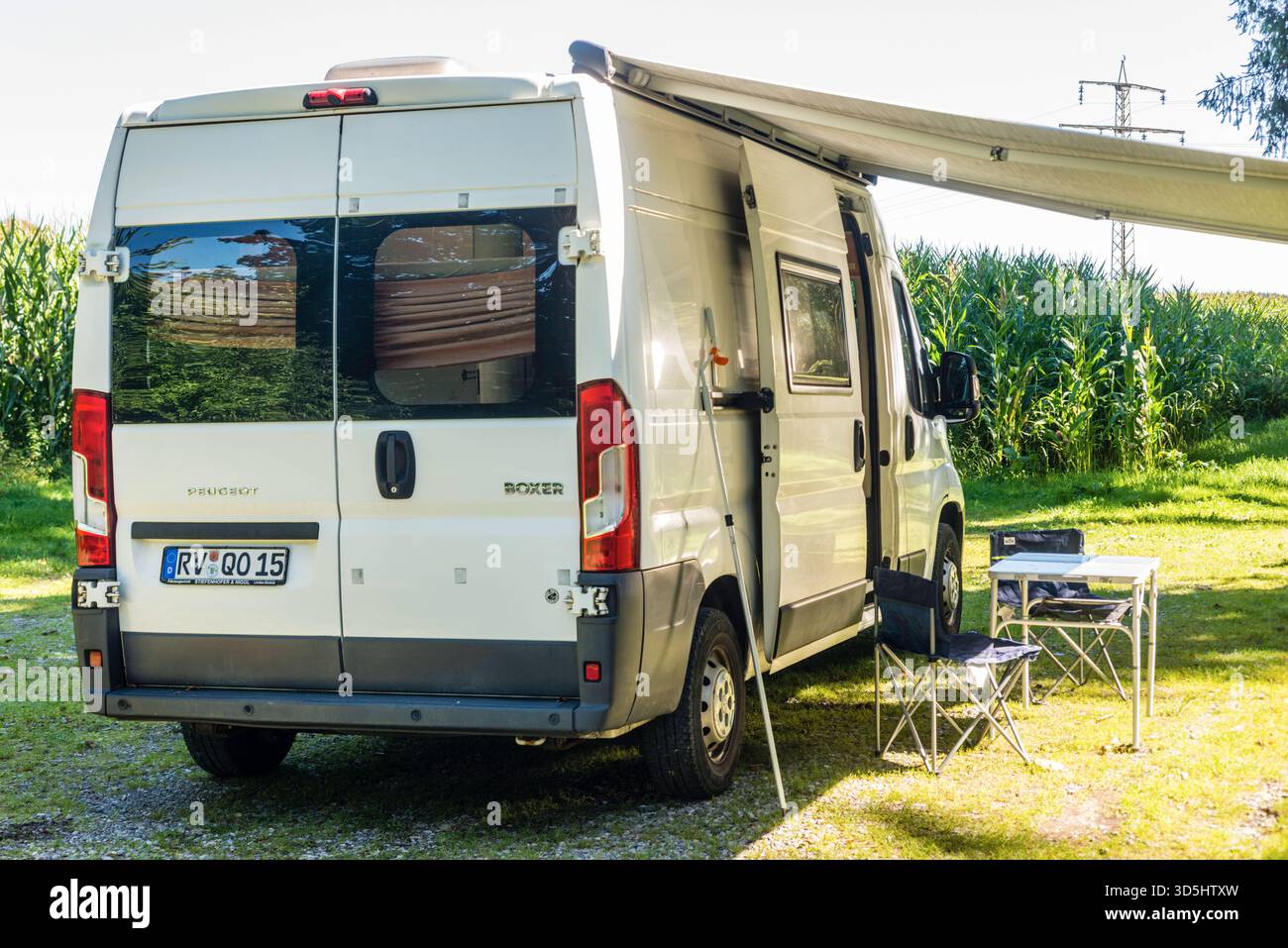 Ein Campingfahrzeug steht auf einer Wiese an einem Waldrand, es stehen  Campingmbel davor unter der ausgefahrenen Markise, Deutschland. Mit einem  Campervan unterwegs *** A camper van is parked on a meadow at