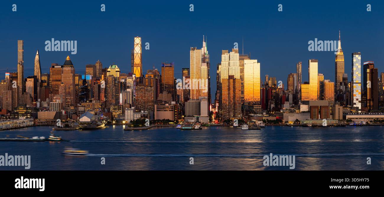 New York City panoramic evening view of Midtown Manhattan skyline from across the Hudson River, with skyscrapers illuminated by the last sunset light Stock Photo