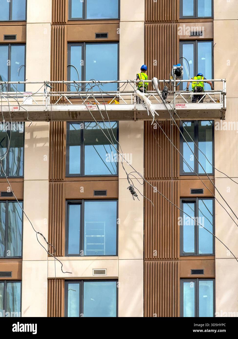 Cardiff, Wales, UK - 16 July 2025: Construction workers on a platform suspended high up on the outside of a new block of flats in Cardiff city centre. - Smartphone Captured Stock Image
