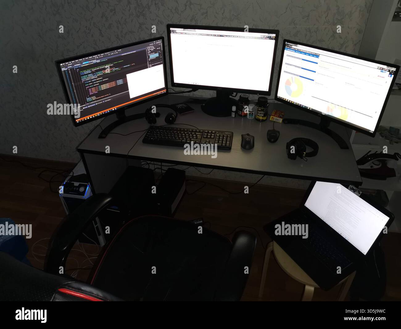Triple monitor developer workstation with laptop in home office Stock ...