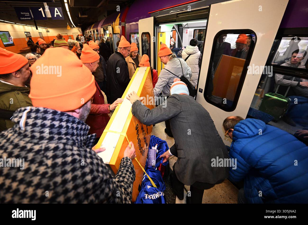 Munich, Germany. 16th Nov, 2025. The Lach- und Schießgesellschaft sign is loaded onto an S-Bahn train by members of the Münchner Lach- und Schießgesellschaft on a trolley at the Marienplatz S-Bahn station. The Münchner Lach- und Schießgesellschaft moves from Haimhauserstraße to the Fat Cat (Alter Gasteig) at Rosenheimer Platz by subway and S-Bahn. Credit: Felix Hörhager/dpa/Alamy Live News Stock Photo