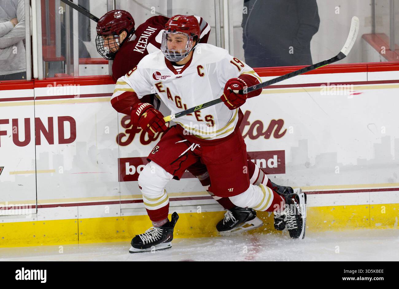 Boston College forward Brady Berard (19) sends Massachusetts defenseman ...