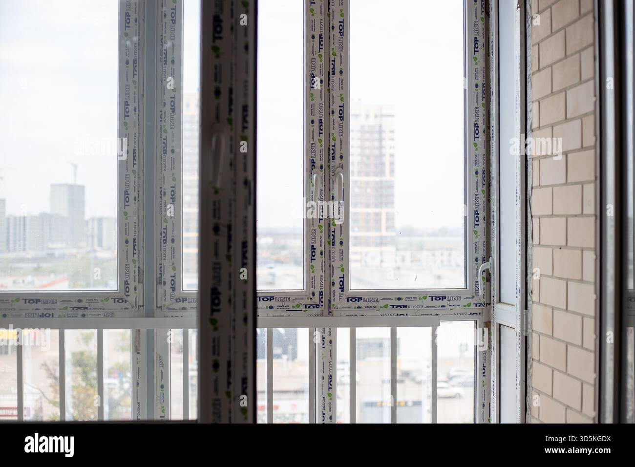 New TOP LINE PVC windows in a room under construction, with a blurred cityscape visible through the glass. Finishing work in a room in a new building. Stock Photo
