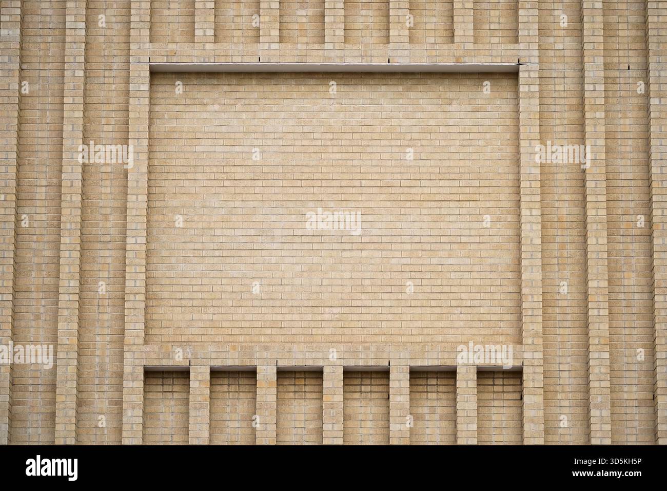 Large brick facade wall with advertisement space framed by architectural brickwork and line elements. Stock Photo