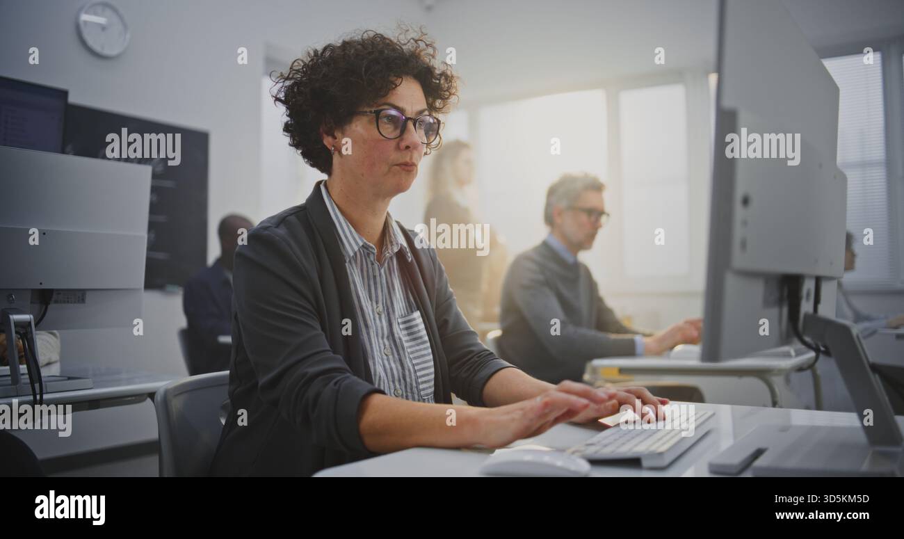Dark Haired Woman in Her Mid Forties Sits at Monitor Coding During IT ...