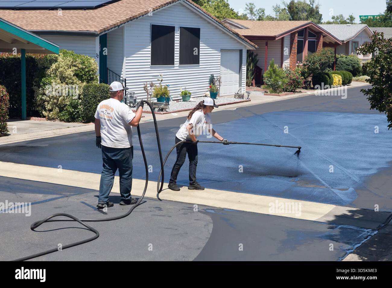 Workers applying liquid asphalt, seal coating, slurry, Mobile Home Community, California. Stock Photo