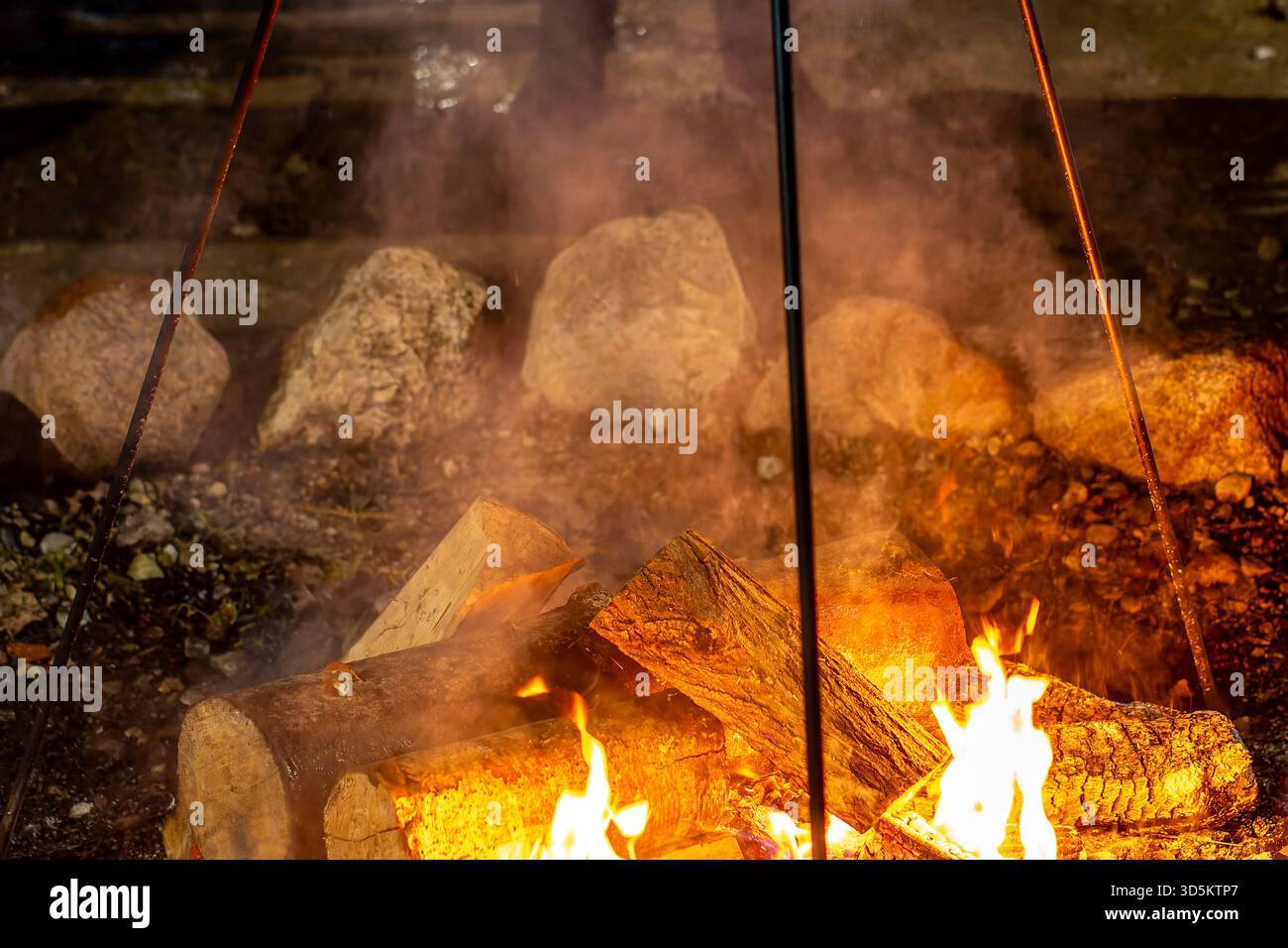 photography with different focus, campfire with cauldron, food being prepared outdoors, stones piled around the campfire for fire safety Stock Photo