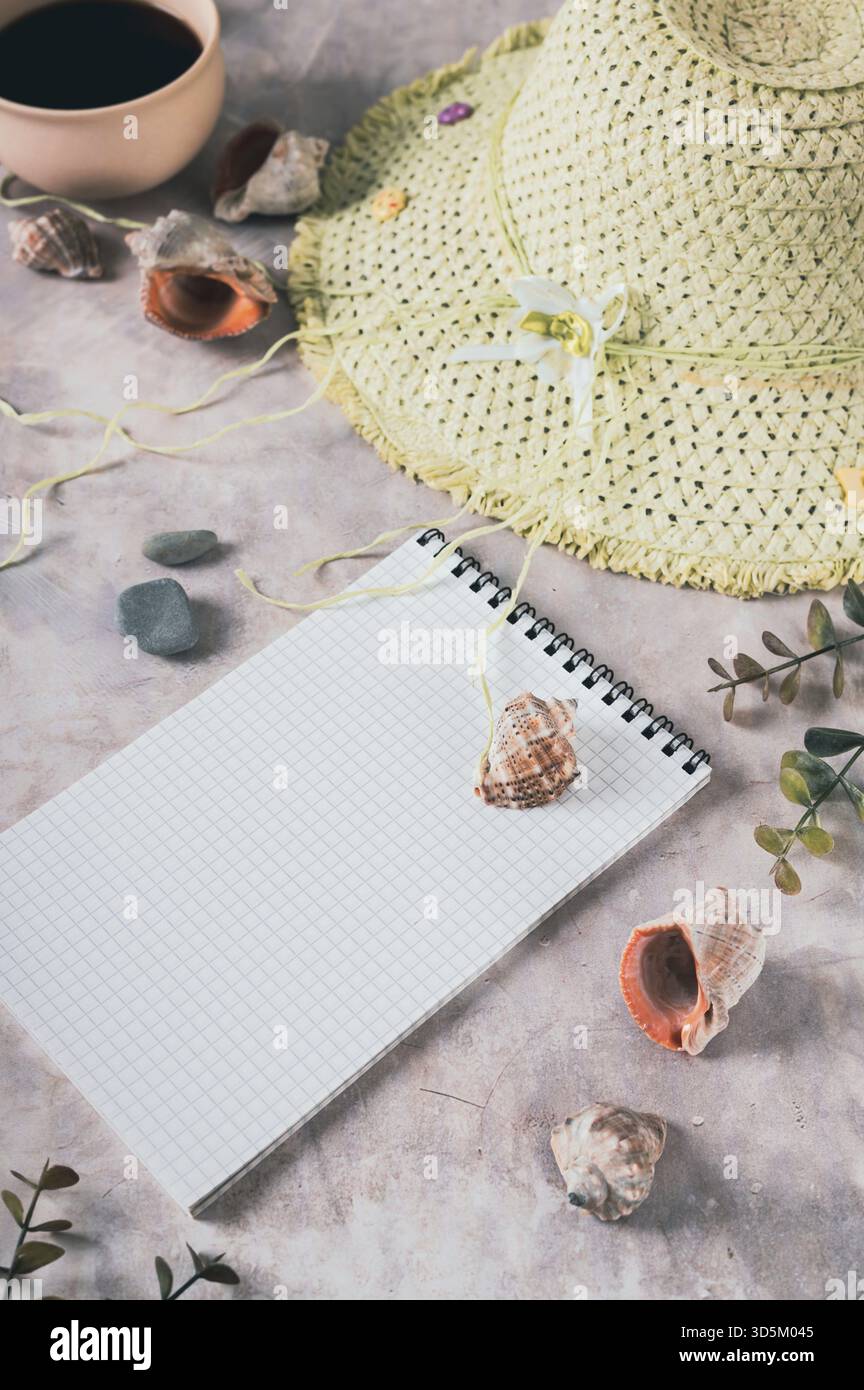 Notebook, beach hat, shells and stones on the table vertical view Stock Photo