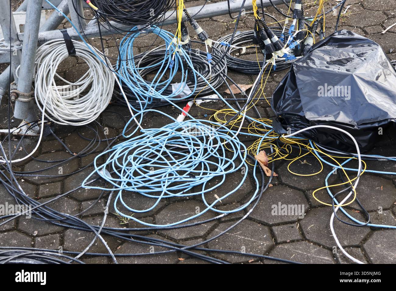 Messy pile of tangled electrical wire and cable on ground outdoors ...