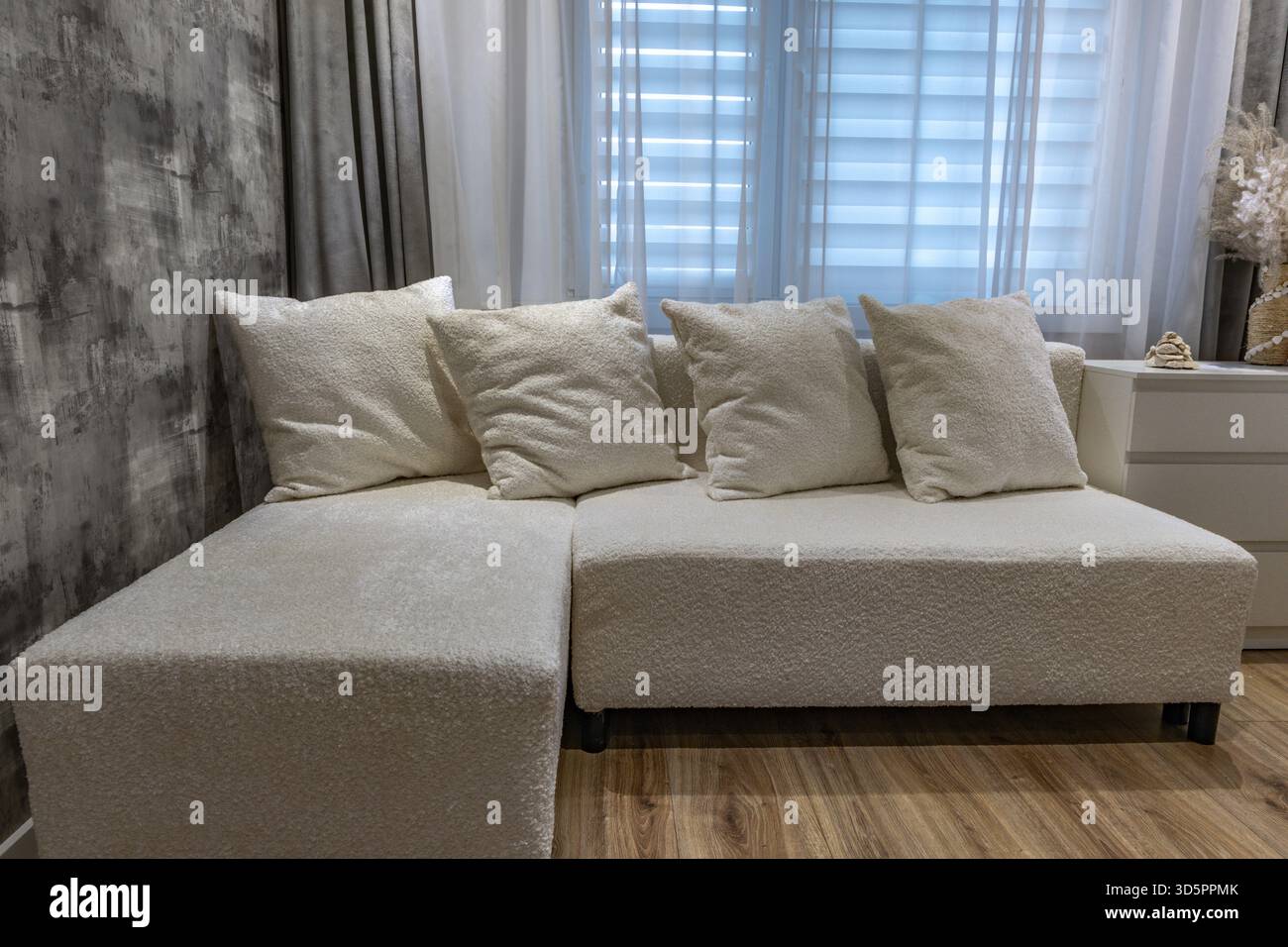 A white sofa made of elegant bouclé fabric in the living room of a ...