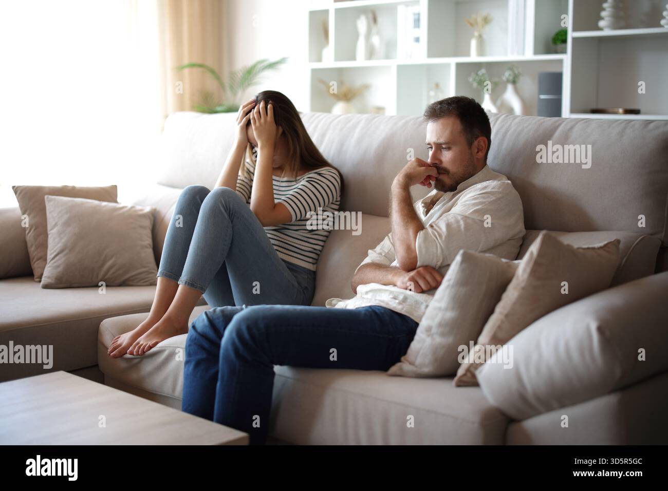 Sad couple complaining after argument sitting on a couch at home Stock Photo