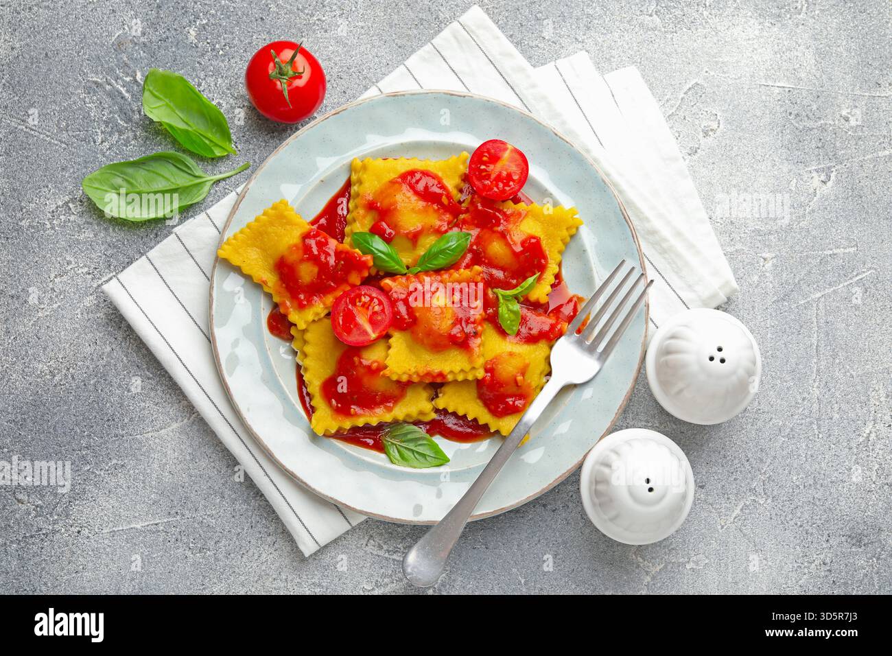 Delicious ravioli with tomato sauce and basil served on grey table ...