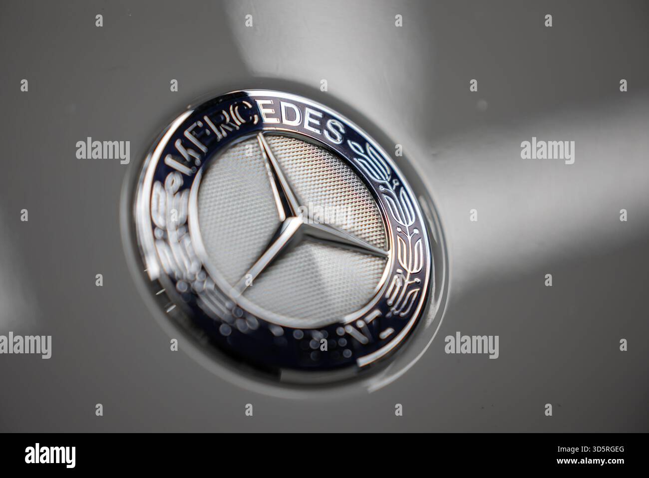 Mercedes Benz emblem macro on silver gray panel in auto workshop Stock Photo