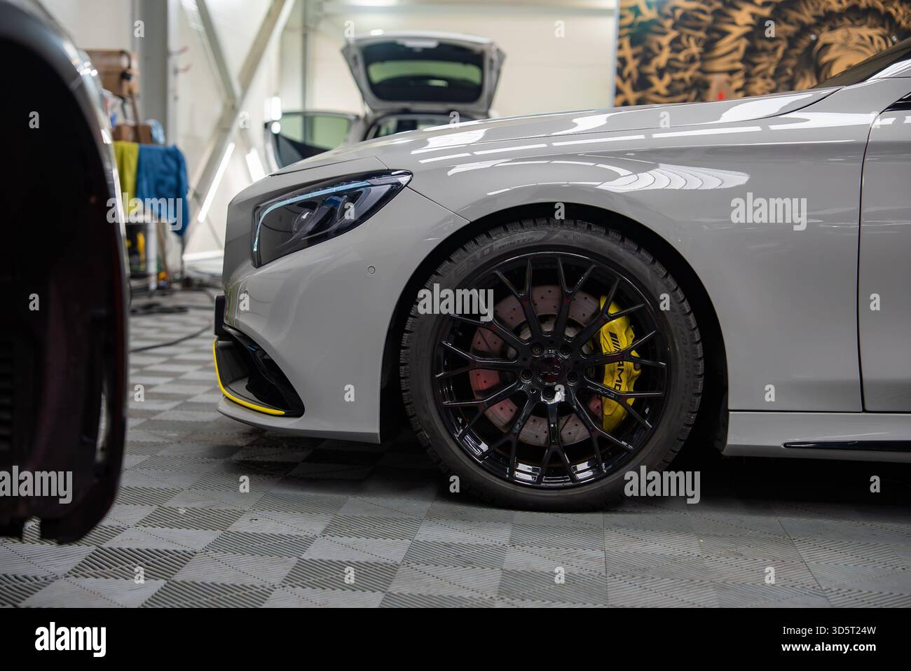 Mercedes Benz AMG front quarter in workshop with yellow calipers Stock Photo