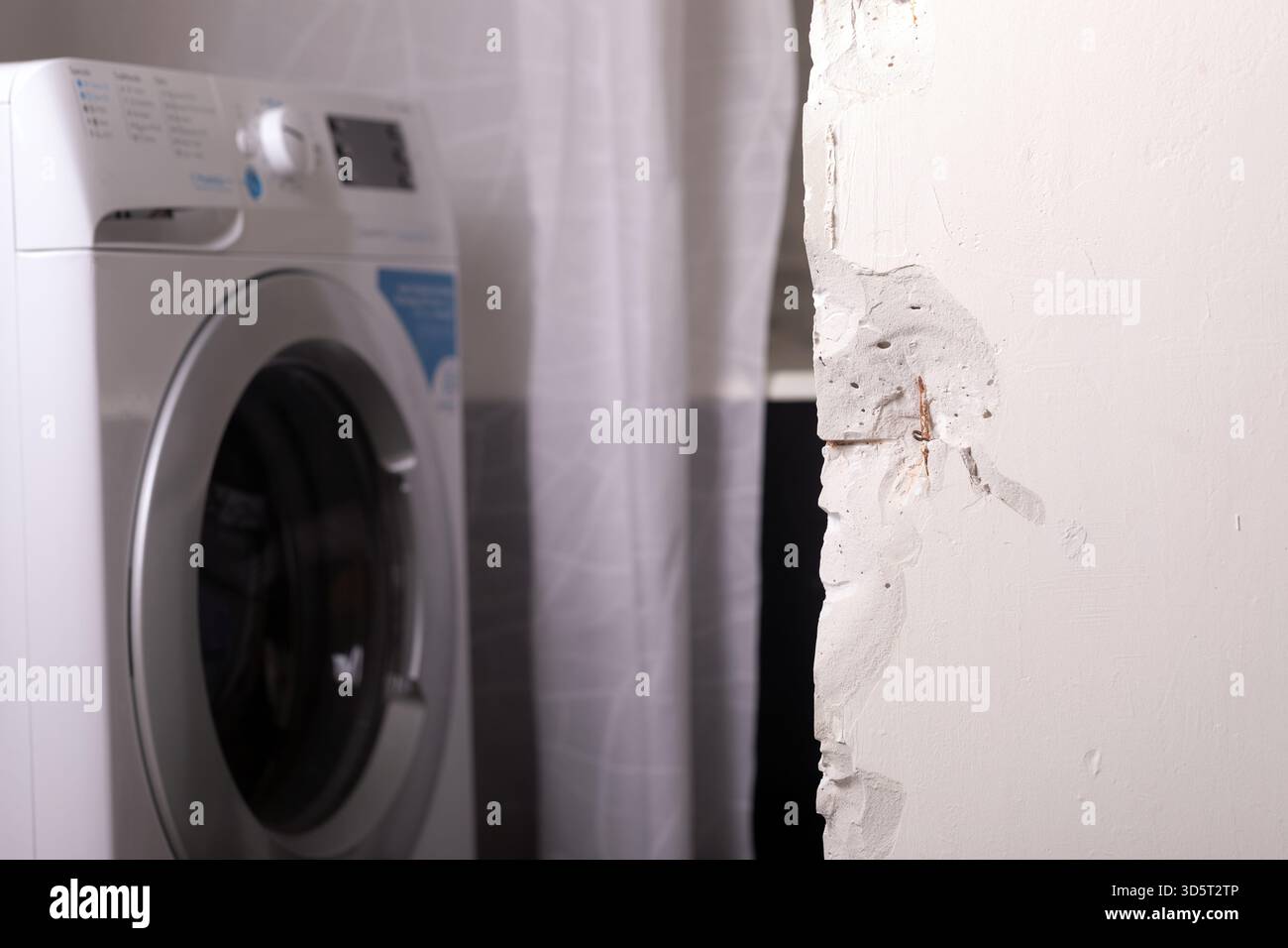 Multiple Washing Machine Rough In Front-loading washing machine beside a white wall with visible damage ...
