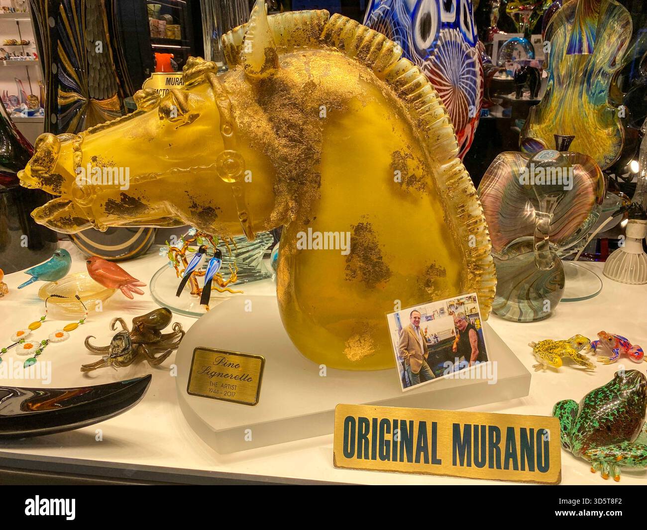 A gold painted hand-carved glass horse head on display in a luxury high-class glassware shop specializing in famous Murano glass in Venice in the Vene - Smartphone Captured Stock Image