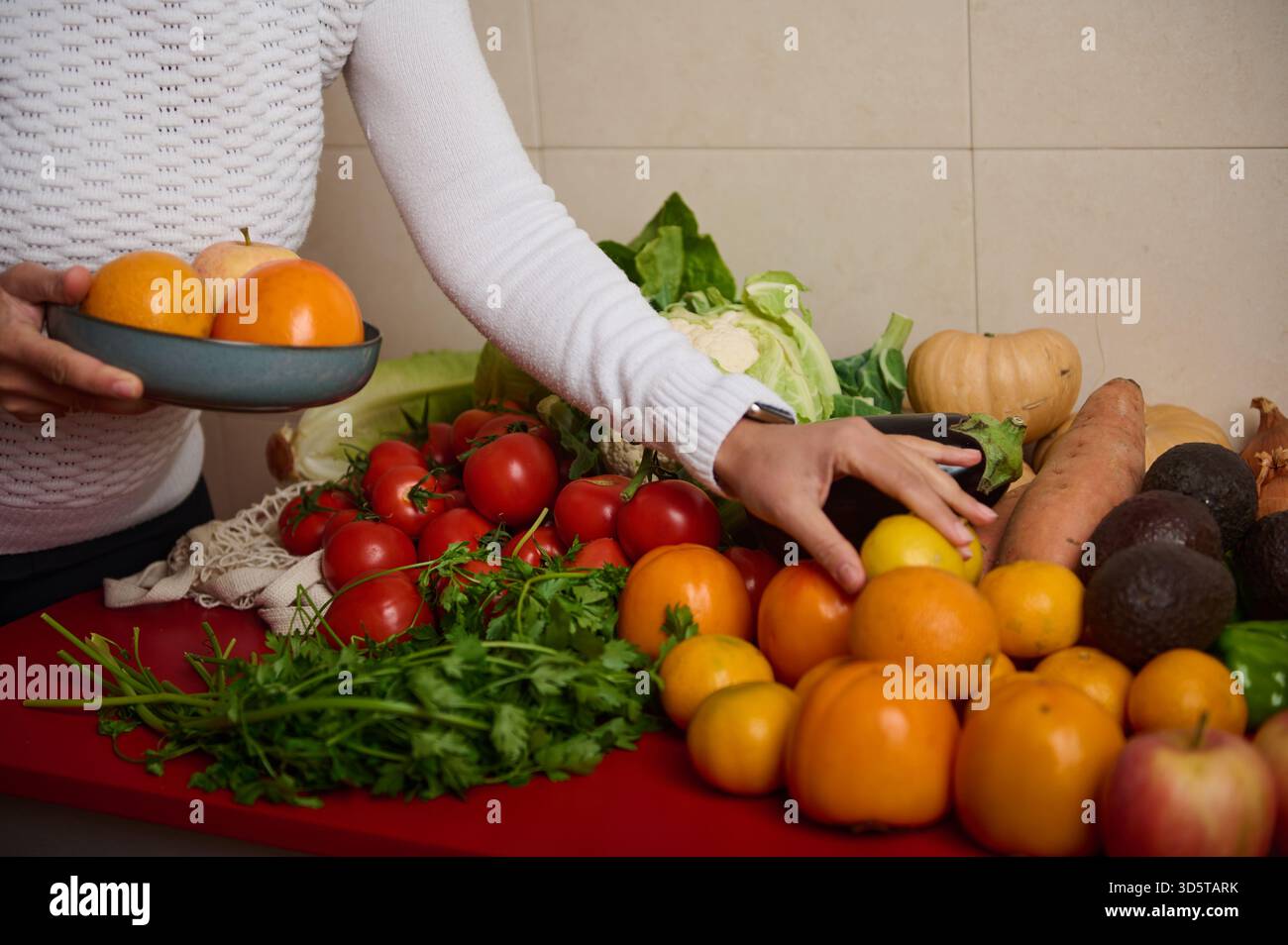 A colorful assortment of fresh fruits and vegetables on a red kitchen ...