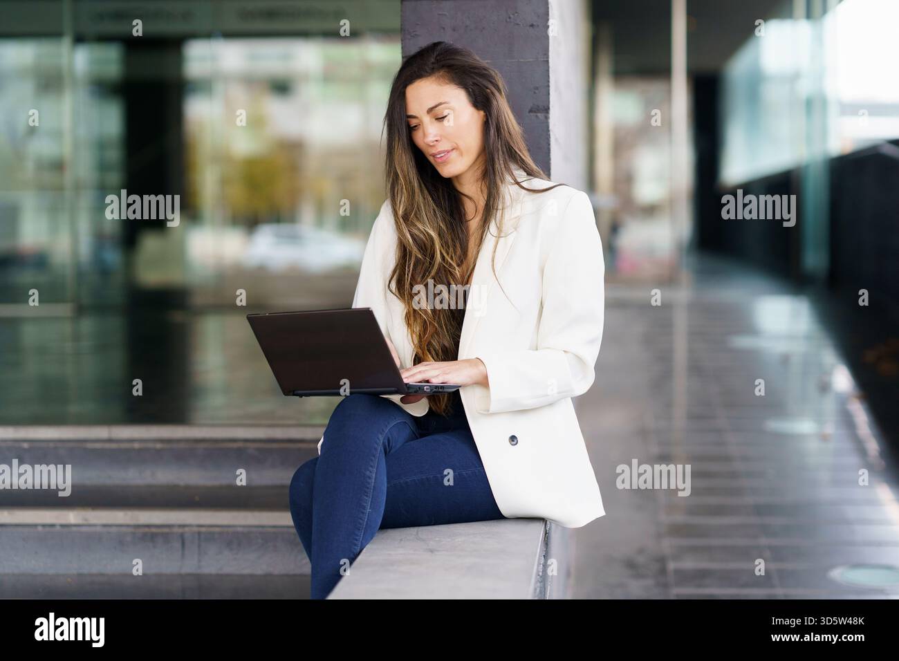 A young professional woman works on her laptop outdoors, highlighting her careerdriven mindset Stock Photo