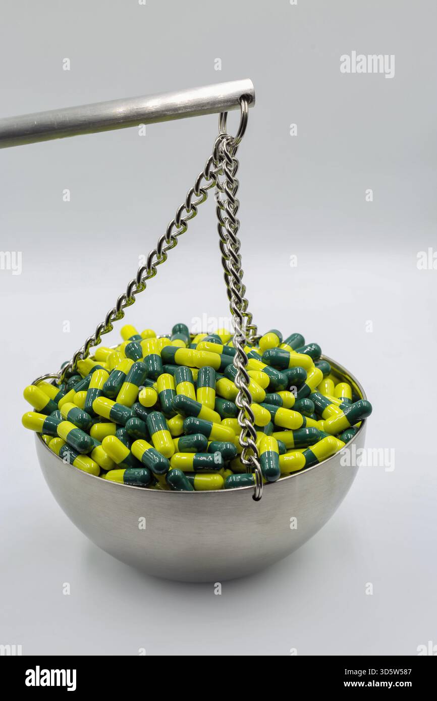 Stainless steel balance scale filled with green and yellow capsules on ...