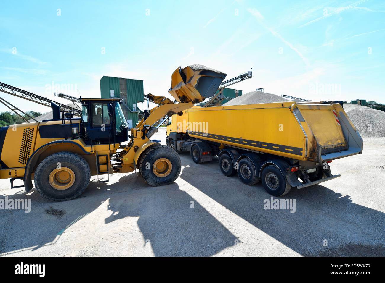 Wheel loader loads a truck with sand in a gravel pit Stock Photo - Alamy