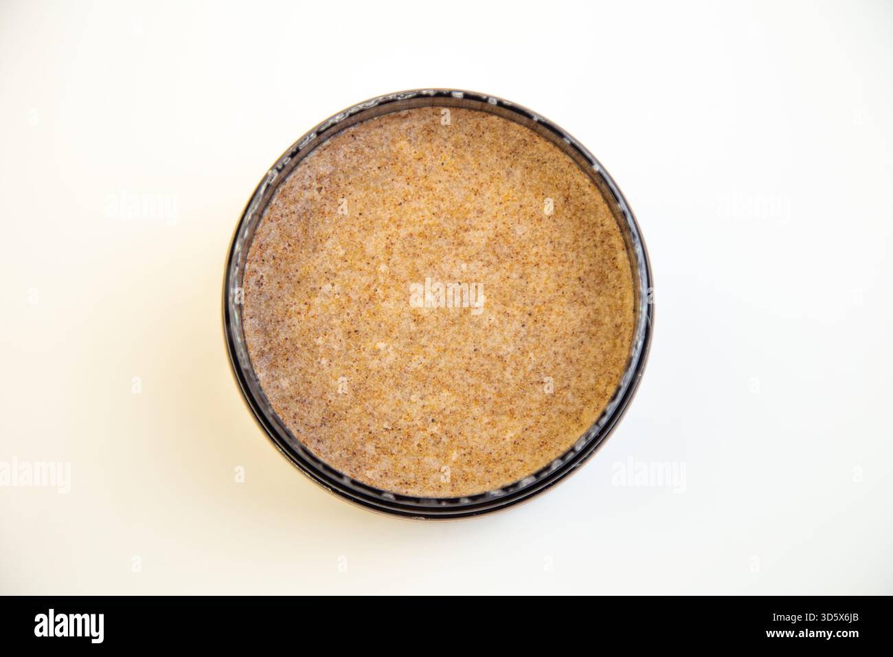 Black round container features a brown textured substance, highlighting smoothness and subtle Stock Photo