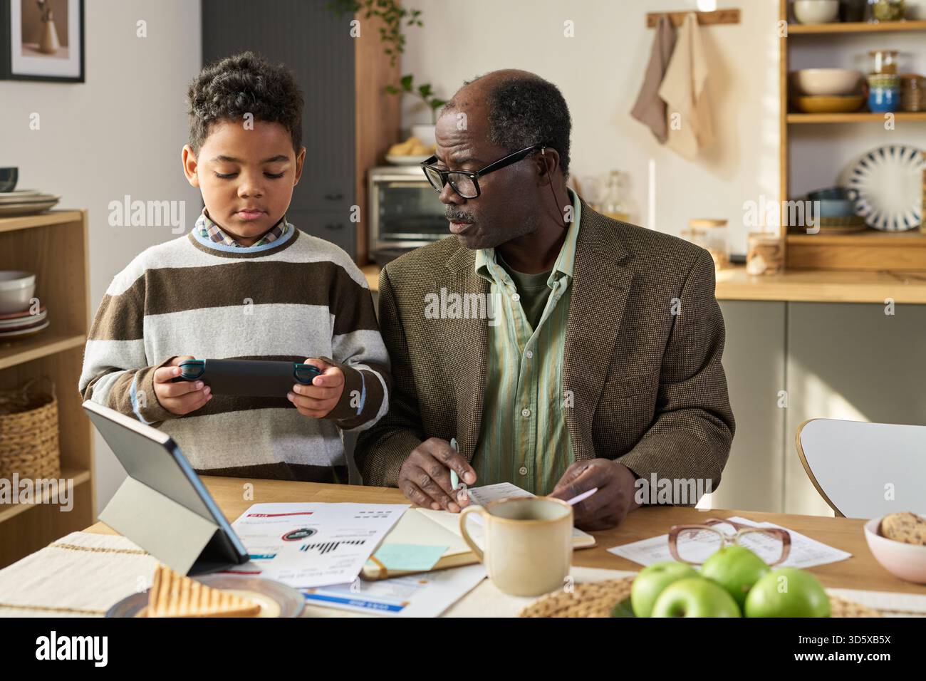 Mature Black Man Teaching Black Boy Using Digital Tablet Stock Photo
