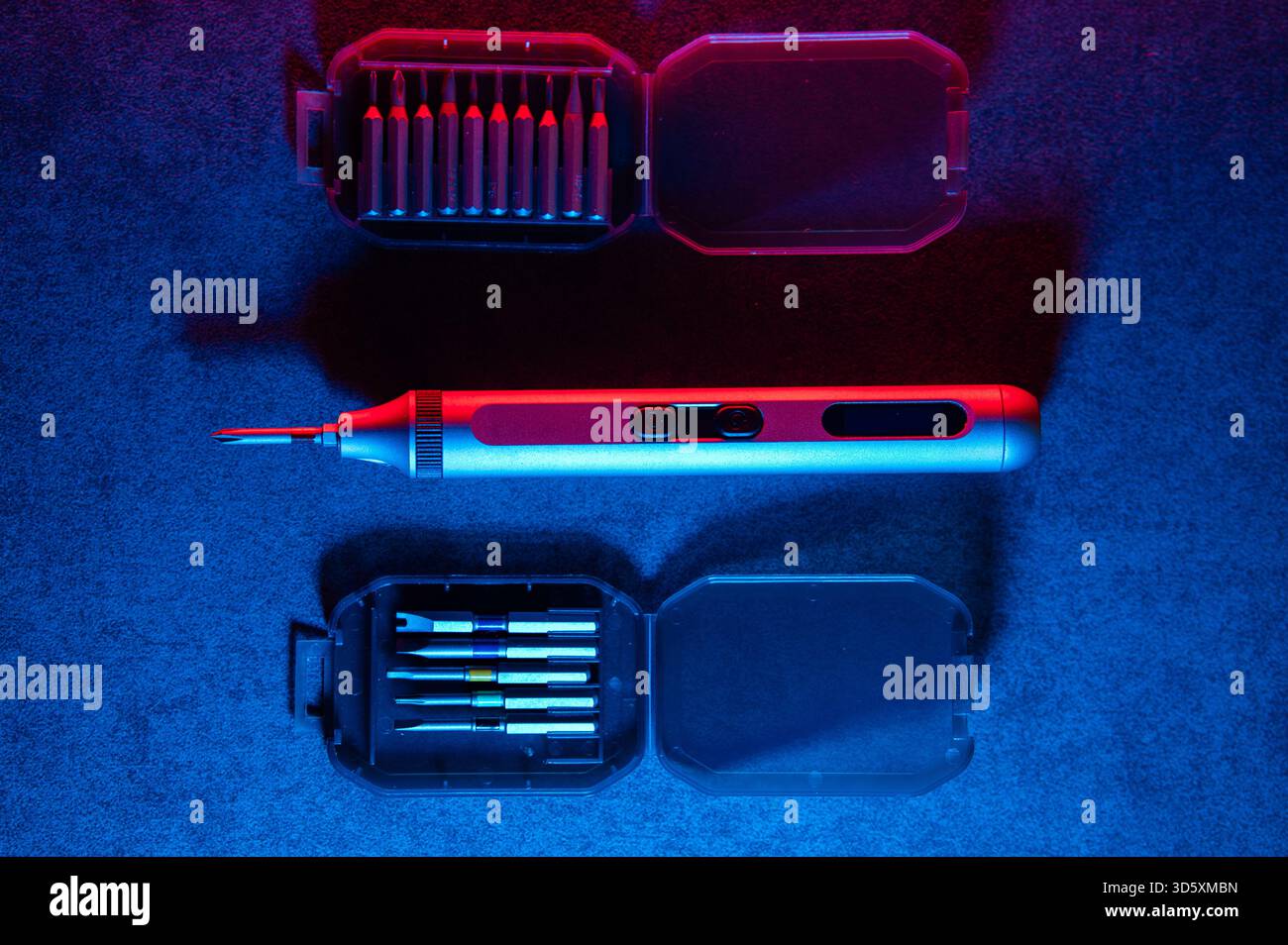 precision electric screwdriver and bits displayed on textured dark surface, product showcase for tool designer, cool blue rim lighting, scattered prec Stock Photo