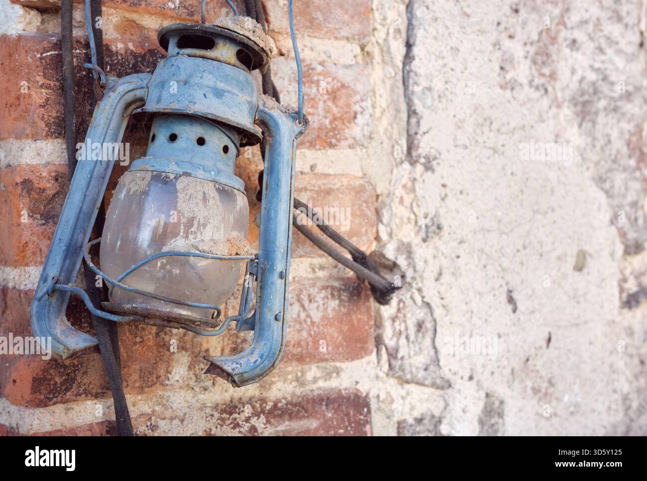Rusty old damaged kerosene lamp on a wall, selective focus. Stock Photo