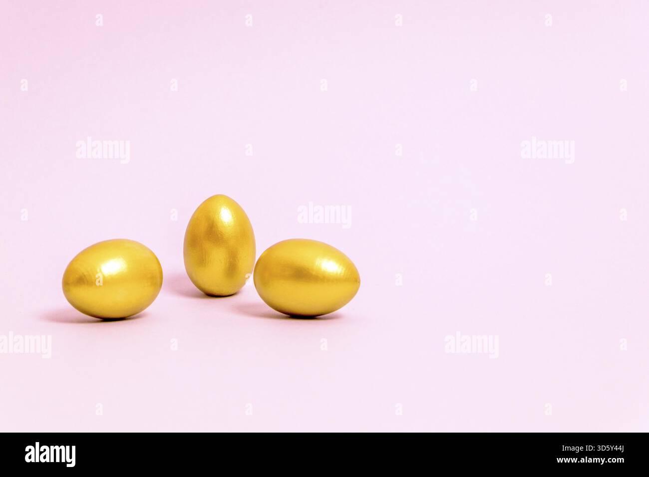 Three Easter eggs decorated with gold paint on a pink background. Concept for Easter, spring. Selective focus. Copy space Stock Photo