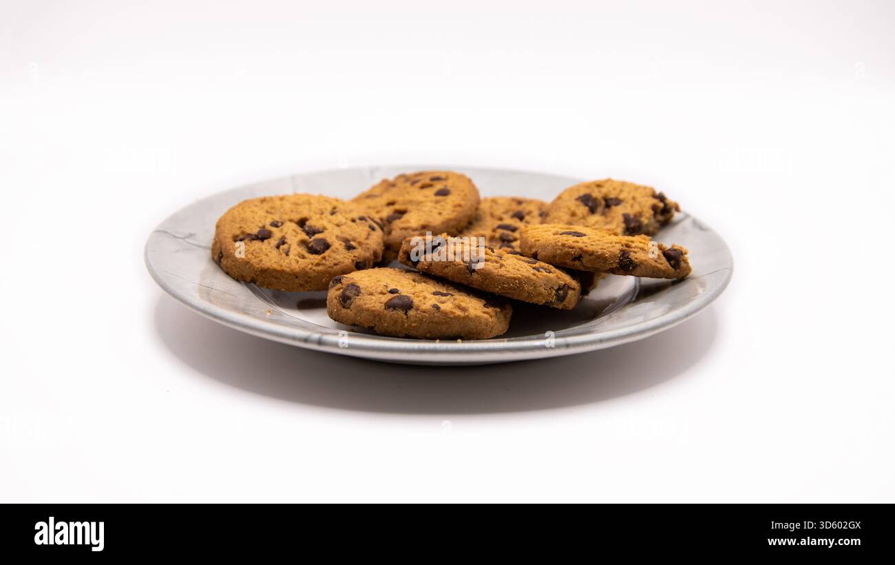 Freshly baked chocolate chip cookies arranged on a plate against a clean white background. Sweet dessert or snack concept. Stock Photo