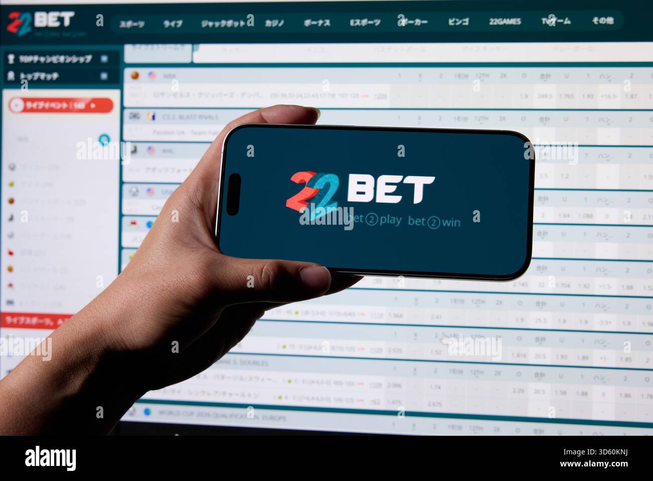 The logo of 22bet is seen on a smartphone and its website is displayed ...