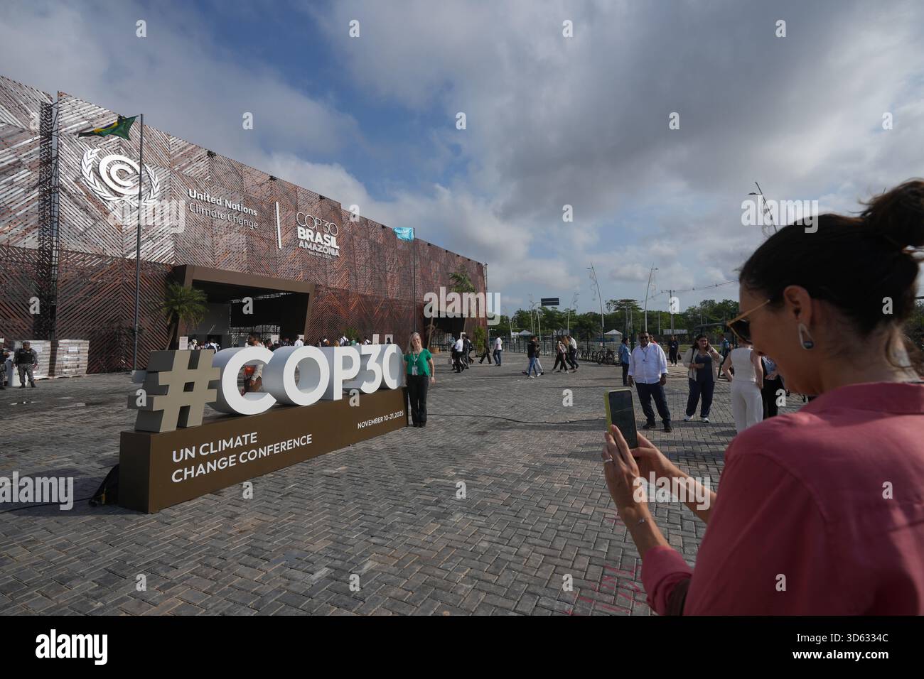 An attendee poses for a photo near a sign for the COP30 U.N. Climate ...