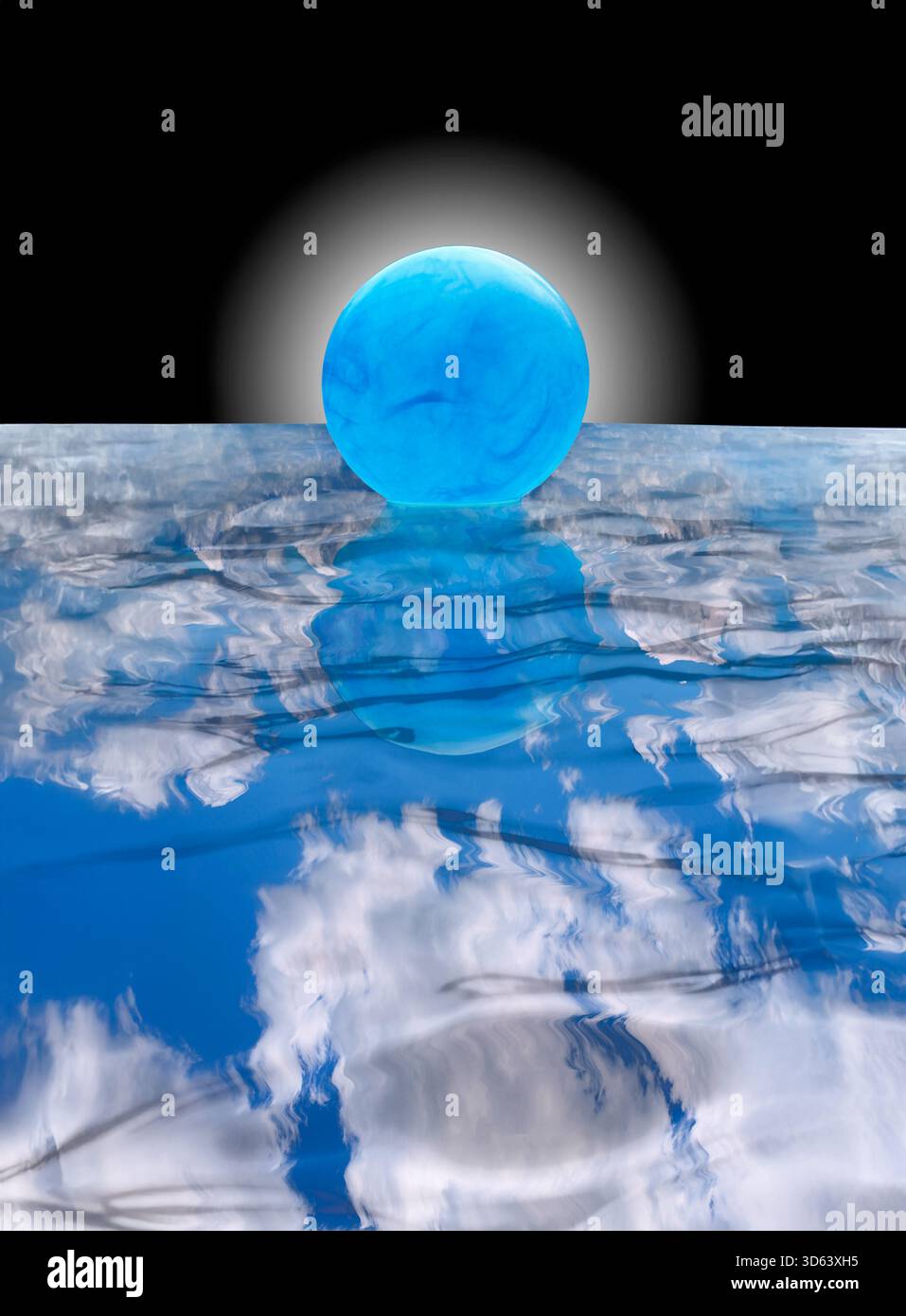 Blue ball floating on water with clouds reflecting Stock Photo