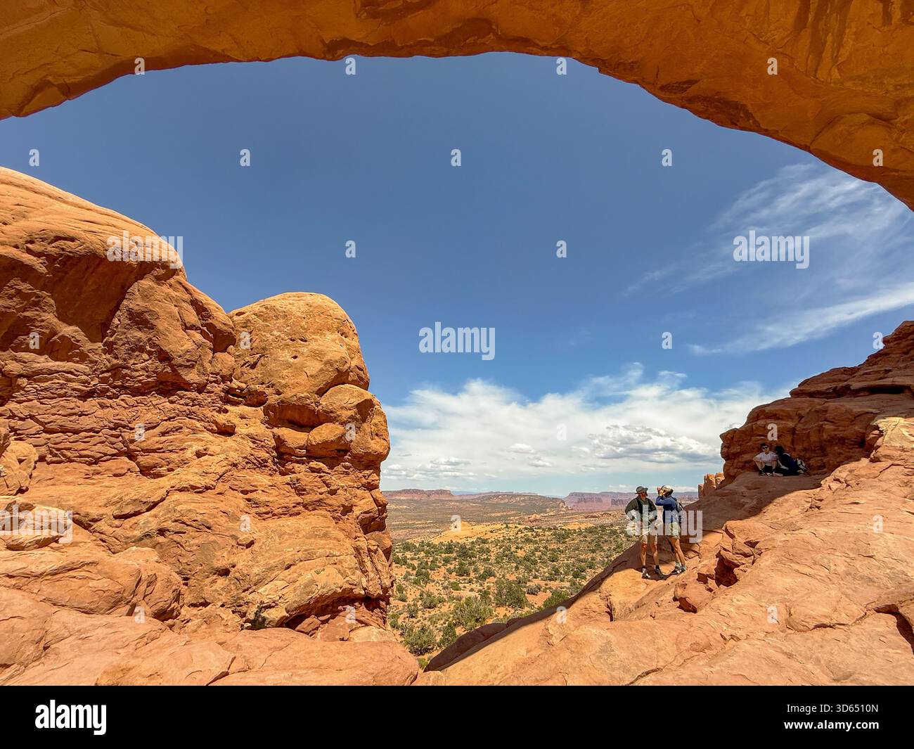 Moab, Utah, USA - 25 May 2025: People on rocks through one of the arches on the Windows Trail in the Arches National Park near Moab, Utah - Smartphone Captured Stock Image
