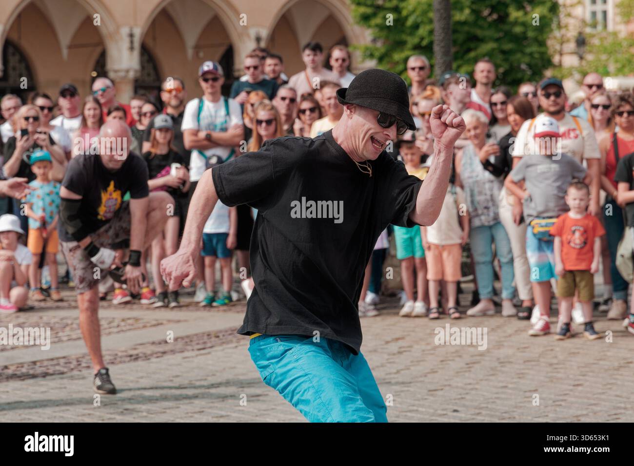 Breakdancer performs energetic footwork during a street show in the Main Market Square, surrounded by a large crowd. Stock Photo