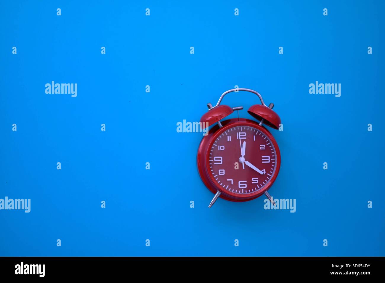 Red analog alarm clock on blue background highlights time awareness ...
